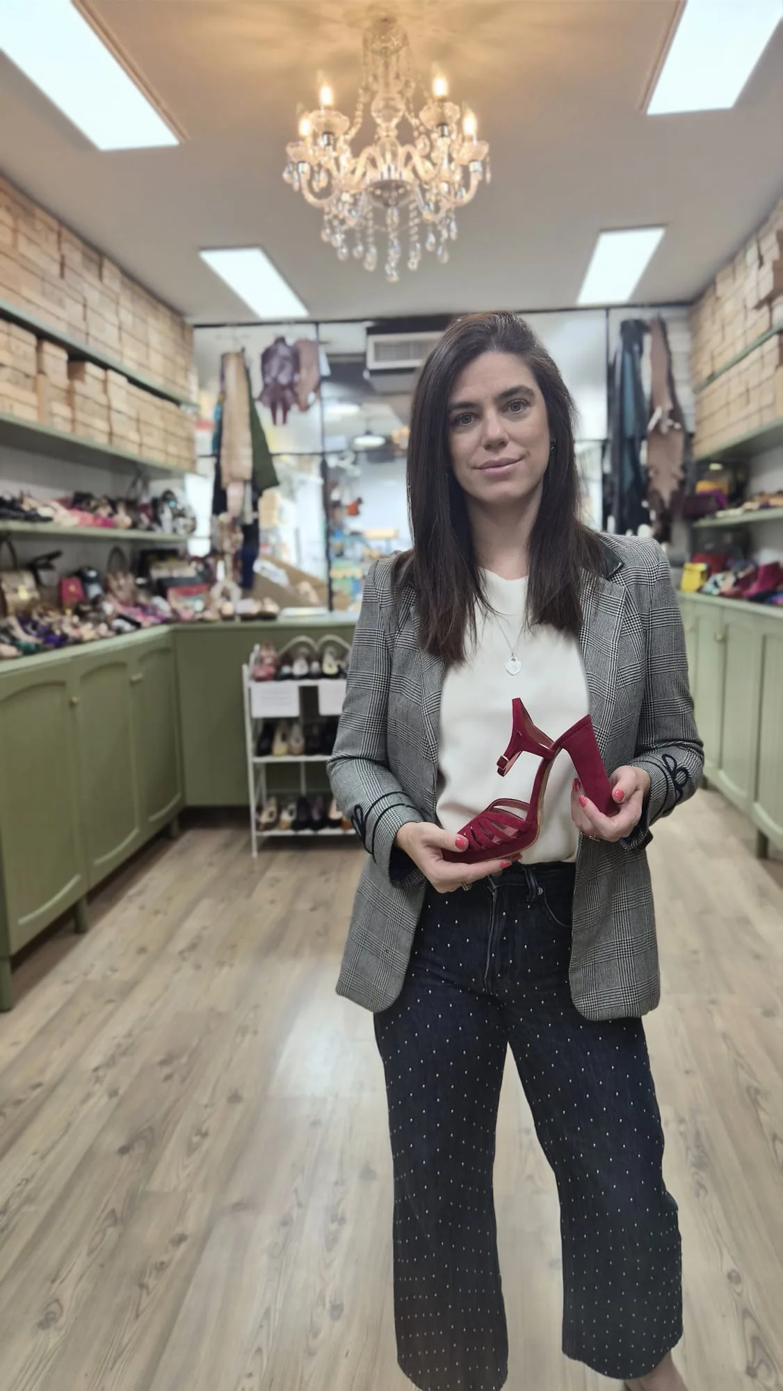 Lupe Ramos en su tienda, con una sandalia roja en las manos